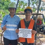Seorang petugas lapangan PT ASM dan warga desa menunjukkan kertas bertuliskan detail program air bersih di lokasi sumur bor di Desa Umera, Kecamatan Pulau Gebe, Kabupaten Halmahera Tengah. Realisasi Program PPM seperti penyediaan sarana air bersih ini tetap berjalan sebagai fokus utama perusahaan meskipun sedang mengawal proses hukum Peninjauan Kembali (PK) di tingkat pengadilan. (Foto: Dok. PT. ASM)